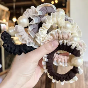 Close up of elegant ruffled lace hair scrunchies decorated with large shiny pearls.