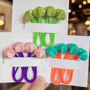 Detailed close-up of colorful faceted pentagram hair ties on cards with vibrant elastic bands.