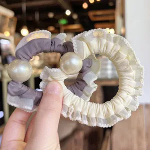 Detail view of elegant pearl ruffled hair scrunchie, soft mesh fabric, cute hair accessory.