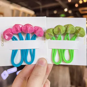 Close-up detail of colorful faceted star hair ties with elastic bands on white cards.