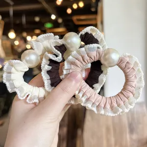 Close-up detail of stylish pearl hair scrunchies with delicate lace ruffle edges for daily hair styling.