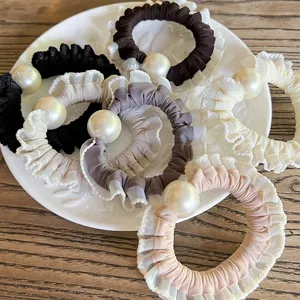 Close-up detail shot of elegant ruffled pearl hair scrunchies set in various chic colors.