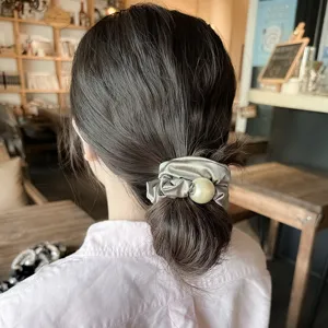 Detailed view of grey satin hair scrunchie with large pearl decor, elegant pony tail holder.