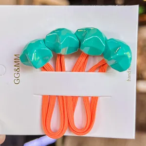 Colorful faceted star hair ties detail shot, vibrant fluorescent green stars with orange rubber bands for kids.