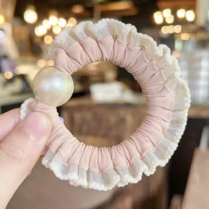 Detail view of the elegant pink hair scrunchie with white lace and a large faux pearl for women.