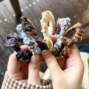 Λεπτομερής φωτογραφία από κομψά σατέν scrunchies με διακοσμητικές χάντρες σε διάφορα χρώματα.