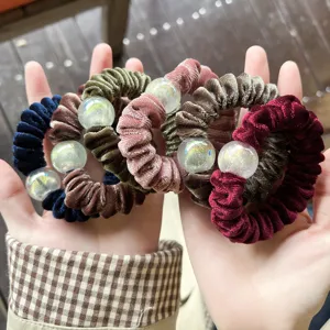 Close-up detail of soft velvet hair scrunchies featuring sparkling glitter beads and ties.
