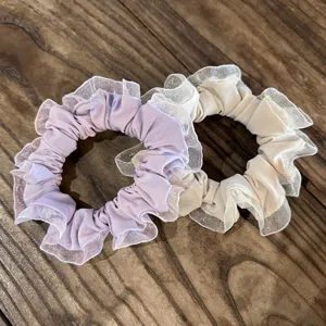 Gros plan chouchous dentelle plissés doux, attaches cheveux élégantes en violet et beige clair.