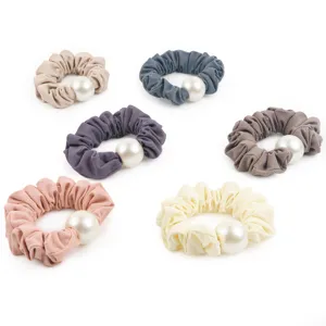 Detailed shot of honeycomb fabric hair scrunchies featuring elegant large white pearls.