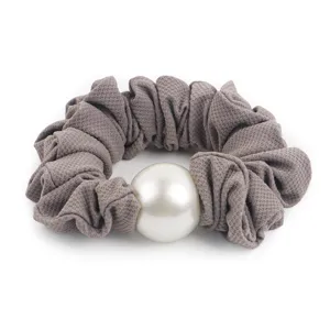 Detailed closeup of grey fabric hair scrunchie featuring a large elegant pearl decoration.