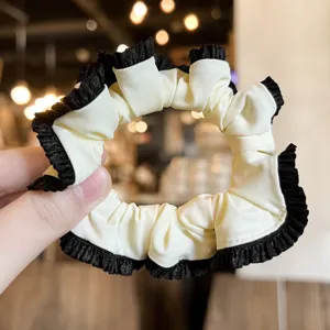 Close-up detail of the elegant black and white ruffled satin hair scrunchie accessory.