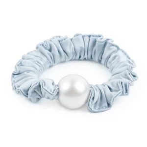 Gros plan detail d'un chouchou en satin bleu clair avec une grande perle artificielle.
