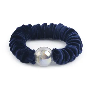 Detailed view of dark blue velvet scrunchie with shiny glitter bead, elegant hair accessory.