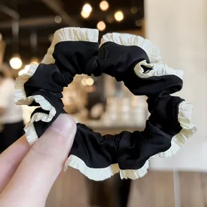 Black and white pleated hair scrunchie detail view, elegant fabric hair accessory for women.
