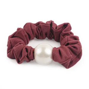 Close-up detail of the burgundy honeycomb silk hair scrunchie with large faux pearl charm.