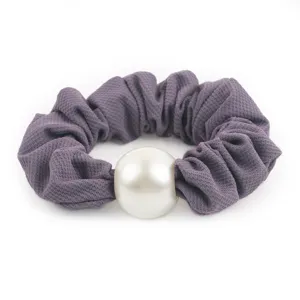 Close-up detail of the purple honeycomb fabric hair scrunchie featuring a large elegant white pearl.