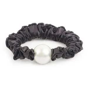 Gros plan détail du chouchou en satin gris foncé avec grosse perle blanche, accessoire.