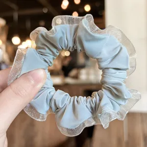 Gros plan détail d'un chouchou bleu clair avec bordure en tulle transparent, accessoire cheveux doux.