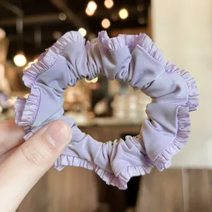 Light purple satin ruffled hair scrunchie close-up, cute elegant hair accessory for women.