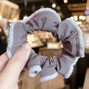 Detail shot of a grey velvet scrunchie featuring a soft white plush trim for autumn winter.
