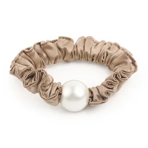 Vue détaillée d'un chouchou en satin marron élégant avec une grande perle blanche.