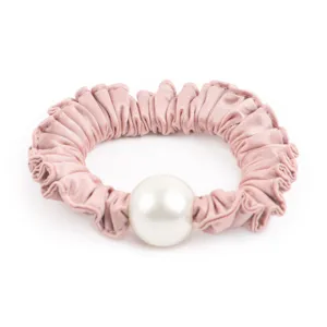 Gros plan détaillé sur le magnifique chouchou en satin rose orné d'une grande perle blanche.