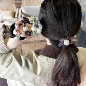 Vue détaillée d'élastiques à cheveux en satin avec grosse perle et bordure plissée.