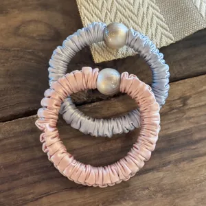 Vue détaillée d'élastiques à cheveux élégants en satin avec de grandes perles roses et bleues.