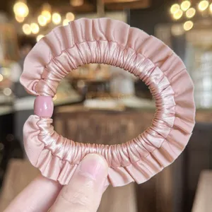 Scrunchie per capelli in raso rosa arricciato vista dettaglio, elegante elastico.