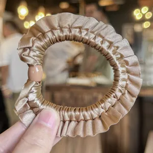Dettaglio scrunchie per capelli in raso arricciato chic, elegante elastico champagne per donne.