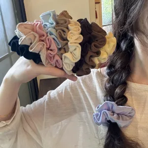 Detalle en primer plano de coleteros grandes para el cabello de lino multicolor estilo diario.