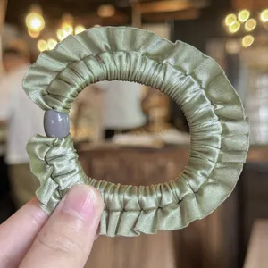 Scrunchie per capelli in raso verde con volant e dettaglio di perla grigia, dettaglio.