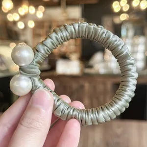 Détail de chouchou en satin avec design de perles doubles pour un style quotidien doux.