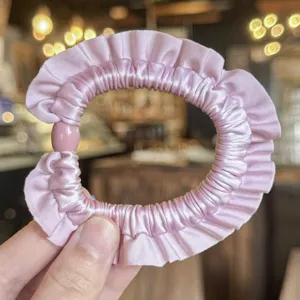 Fascia per capelli arricciata in satin rosa vista dettagliata, accessorio elegante.