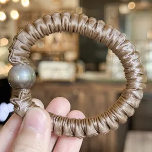 Vue détaillée de l'élastique à cheveux en satin avec perle foncée, haute élasticité.