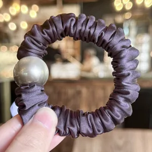 Close-up detail of dark gradient satin hair scrunchie featuring a large metallic bead.