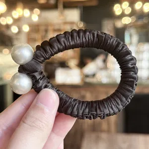 Vue détaillée de l'élastique à cheveux en satin marron foncé avec de superbes perles doubles.