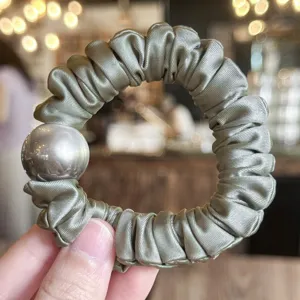 Satin scrunchie detail view with elegant pearl decoration, soft glossy fabric for daily hair styling.
