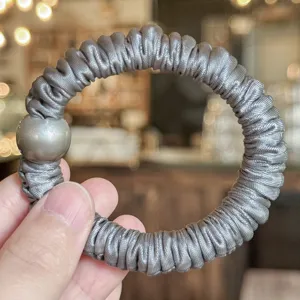 Chouchou en satin gris avec détail de perle ronde, idéal pour un style quotidien élégant.