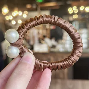 Chouchou de cheveux en satin marron avec perles, accessoire élastique et élégant.