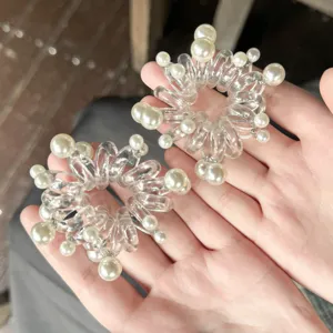 Dettaglio elastico per capelli a filo di telefono trasparente con decorazione di perle finte.
