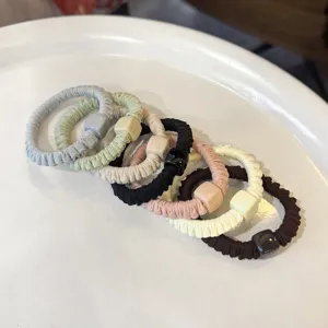 Vista detallada de coleteros suaves plisados para el pelo con cuentas cuadradas, elásticos.
