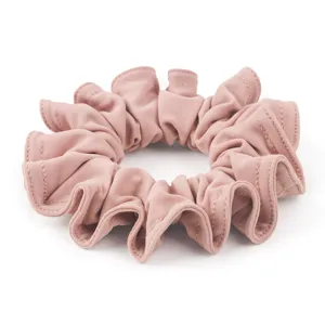 Dettaglio scrunchie in velluto rosa, morbido elastico per capelli plissettato per stile quotidiano.