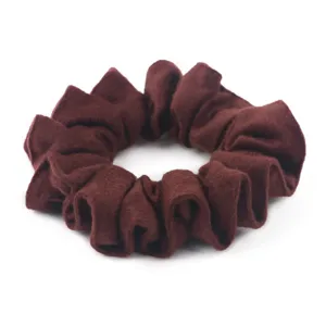 Dettaglio in primo piano dello scrunchie in lana marrone scuro, morbida texture per acconciature.