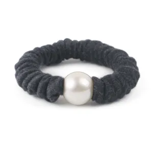Closeup detail of a dark grey wool scrunchie featuring a large central white faux pearl.