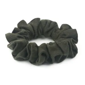Dettaglio in primo piano di scrunchie in lana verde scuro, morbida consistenza in feltro morbido.