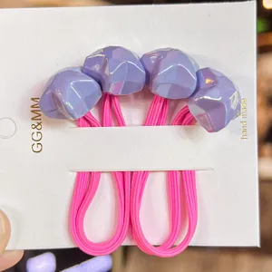 Close-up detail of cute pink elastic hair ties with purple faceted star ornaments on white card.