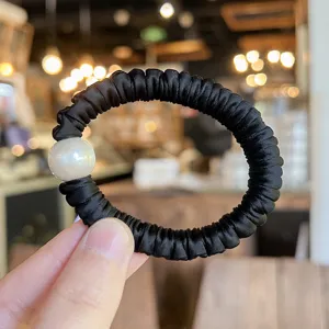 Black satin scrunchie with a large pearl detail, perfect for elegant daily hairstyles.