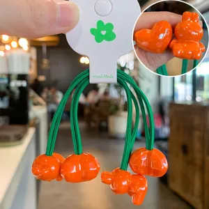 Gros plan détaillé de mignons élastiques à cheveux lapin orange et cœur avec liens verts.