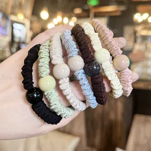 Detailed view of pleated hair scrunchies with large round beads in various colors.